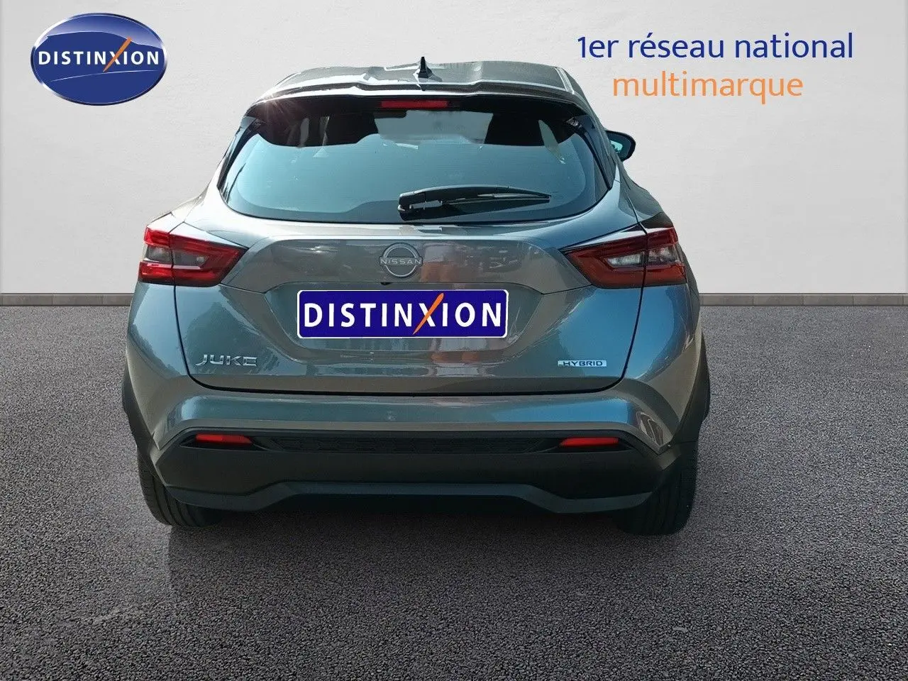 Vue arrière d'un Nissan Juke hybride gris squale métal 2025 avec logo et feux arrière distinctifs visibles.