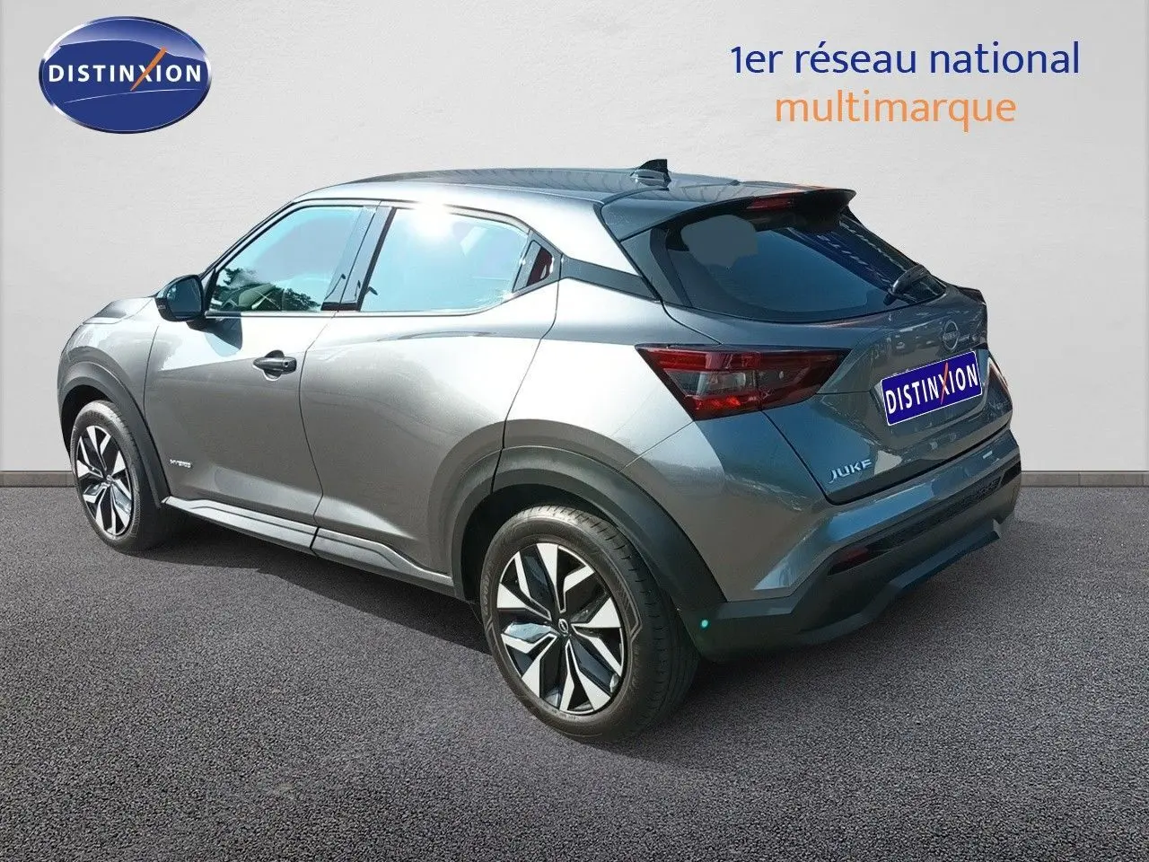 Vue 3/4 arrière droite du Nissan Juke hybride gris squale métal avec jantes distinctives et vitres teintées.