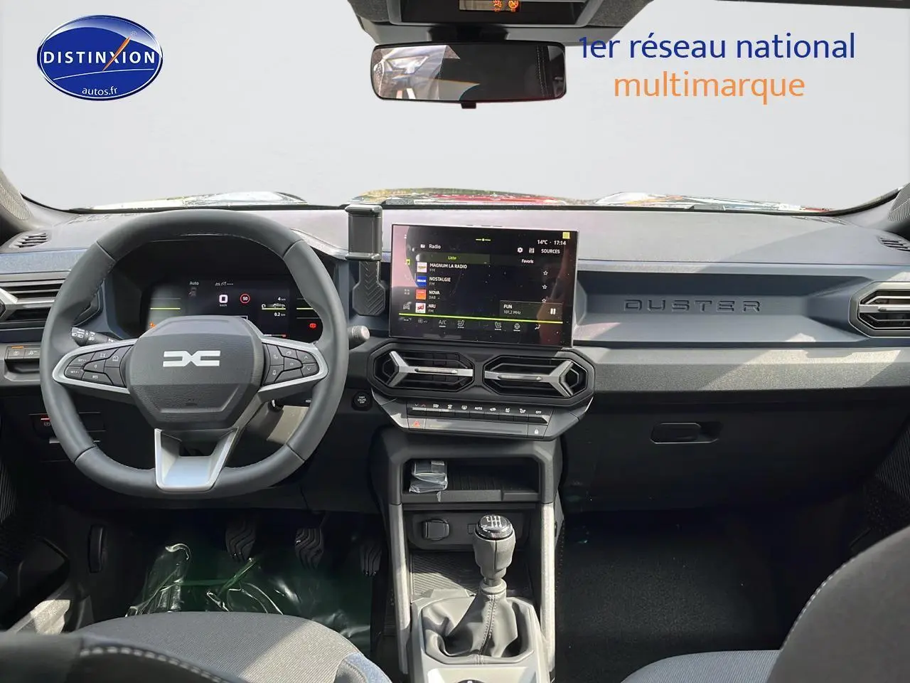 Tableau de bord et volant multifonction du Dacia Duster gris schiste 2025 vus de face, avec écran tactile central.