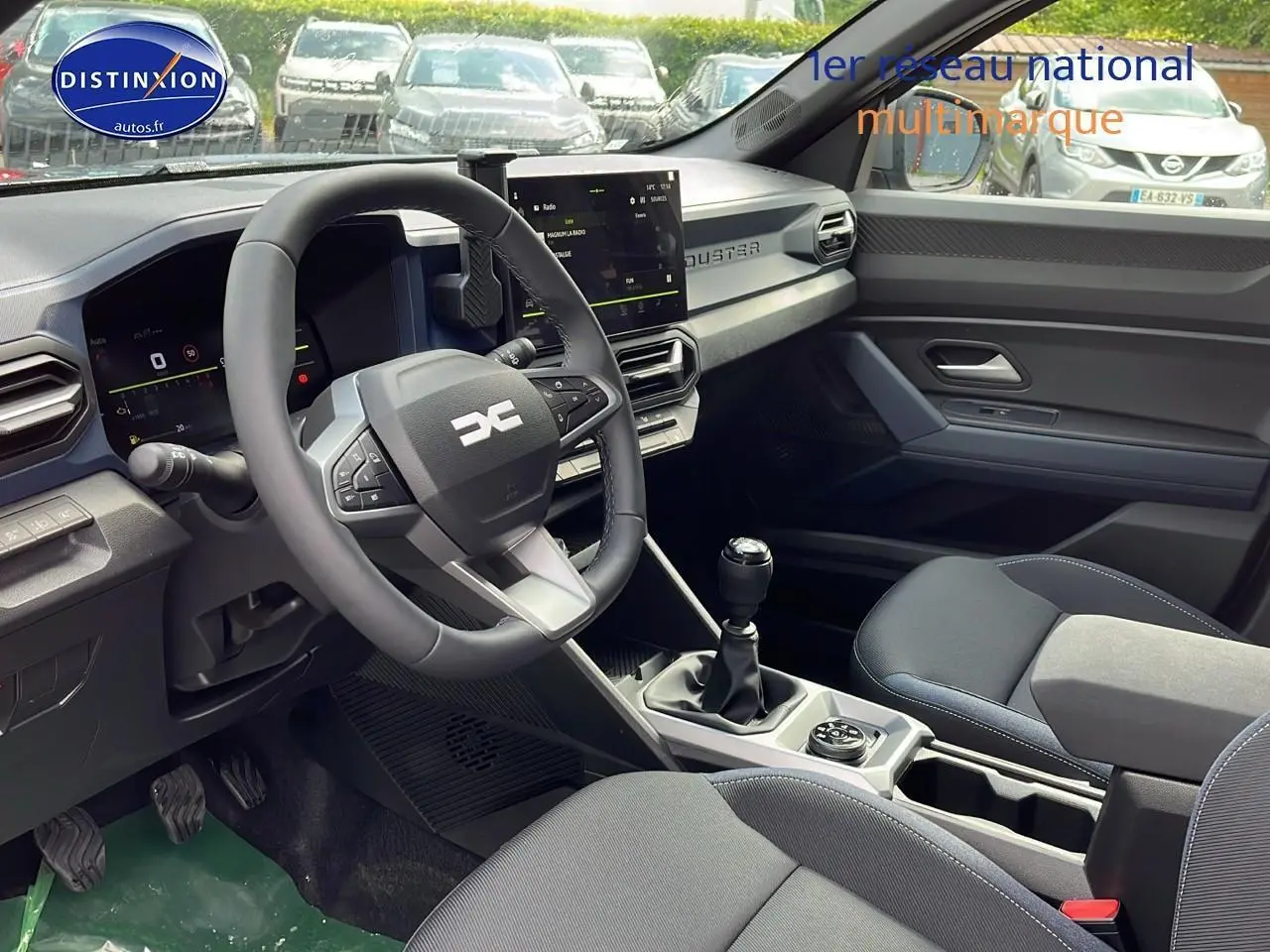 Intérieur du Dacia Duster 2025 montrant le poste de conduite avec volant multifonction, écran tactile et levier de vitesse manuel.