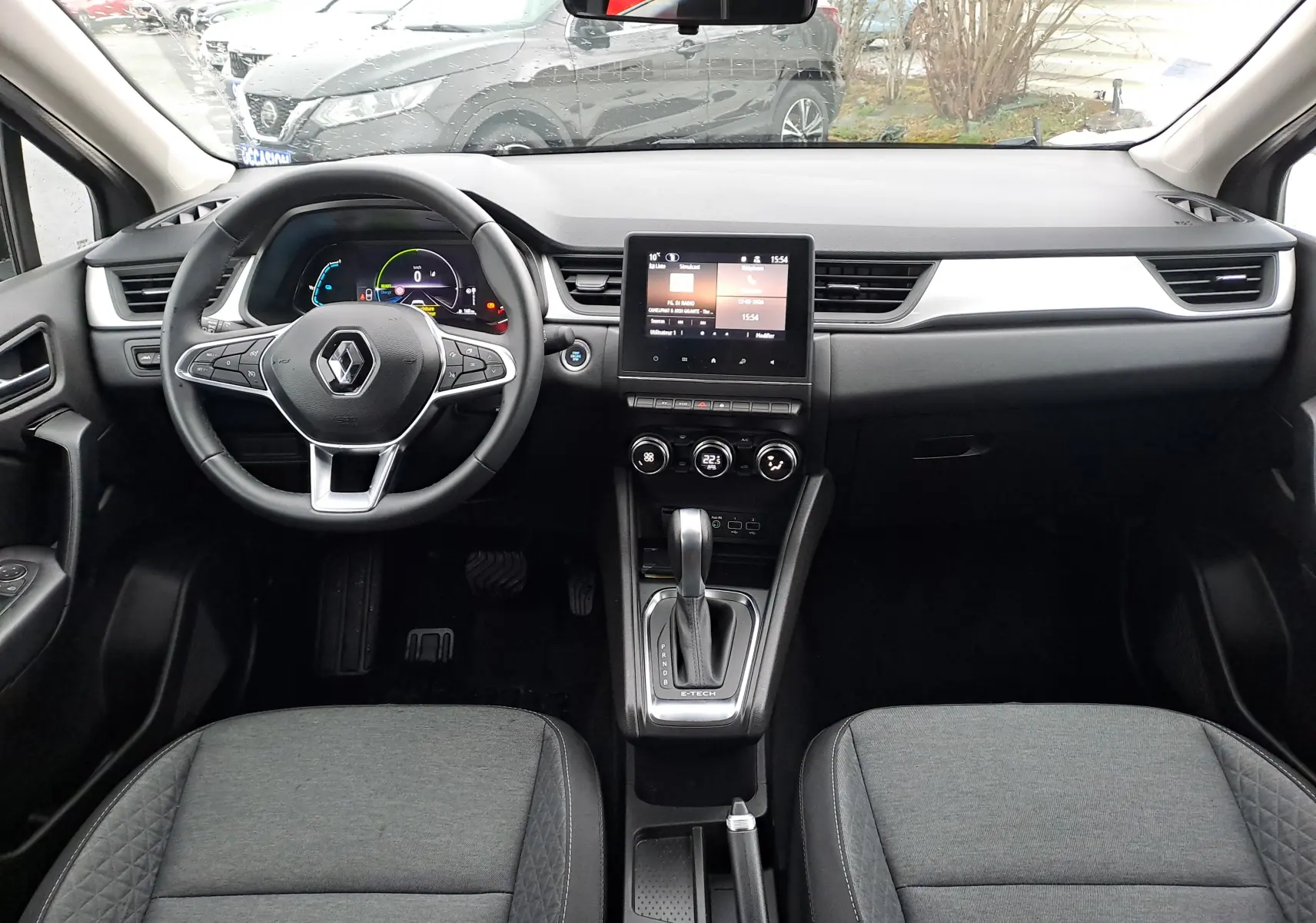 Vue intérieure frontale du tableau de bord du Renault Captur gris cassiopée, avec écran tactile central et volant multifonctions.