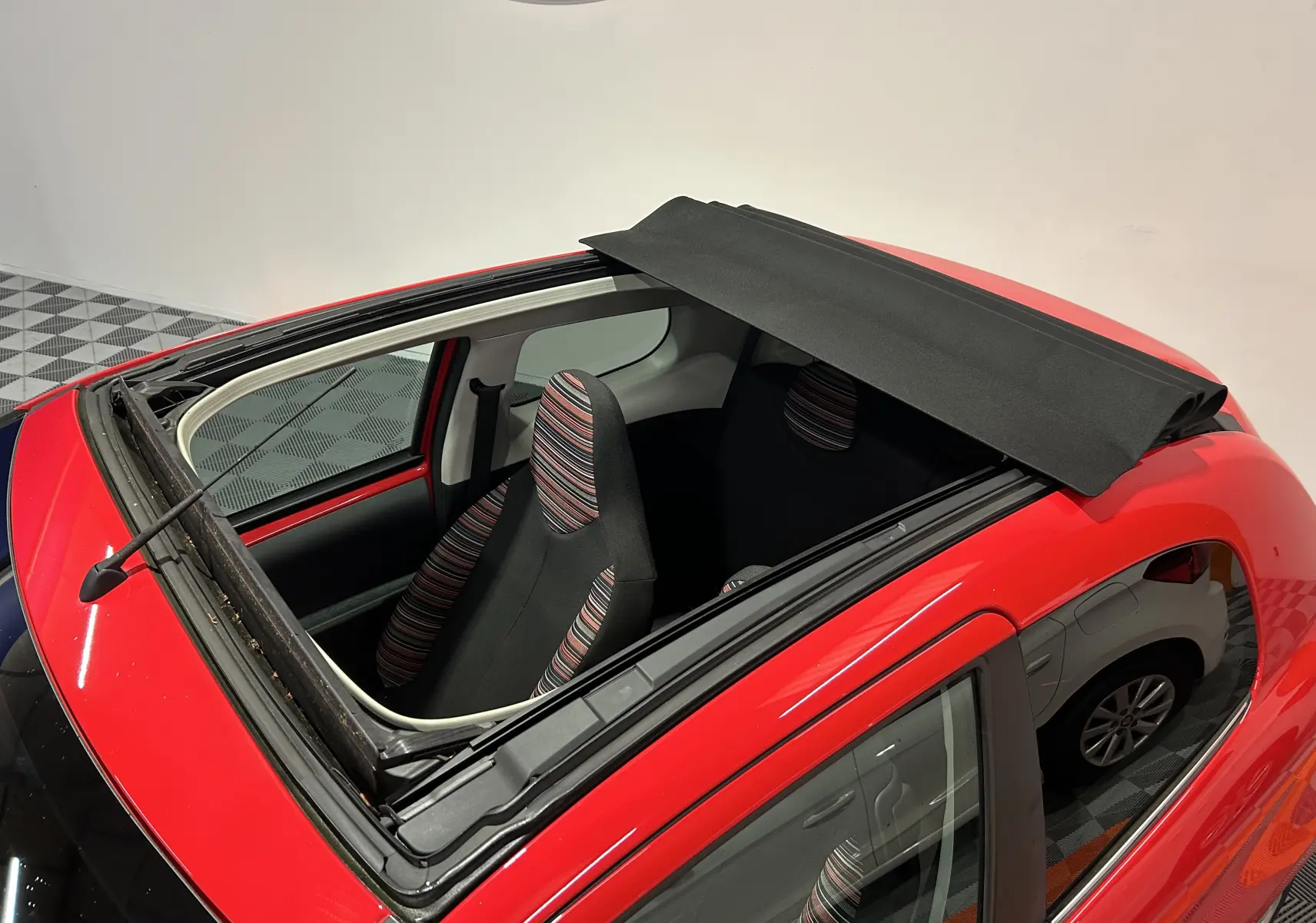 Vue plongeante sur l'intérieur d'une Citroën C1 rouge 2019 avec toit ouvrant Airscape partiellement déployé.