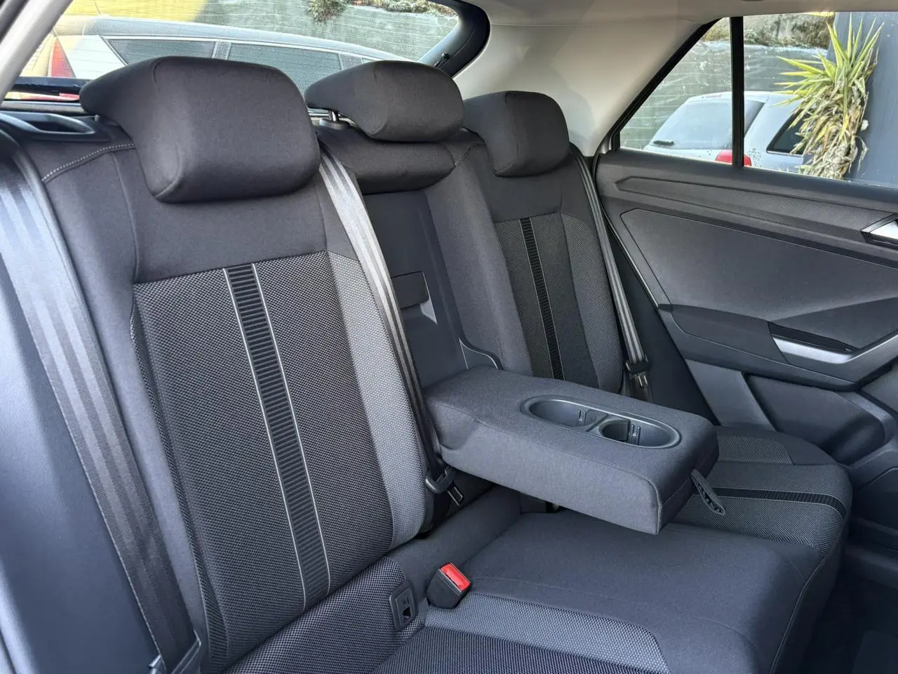 Vue intérieure côté droit des sièges arrière noirs avec accoudoir central déplié du Volkswagen T-Roc 2025.