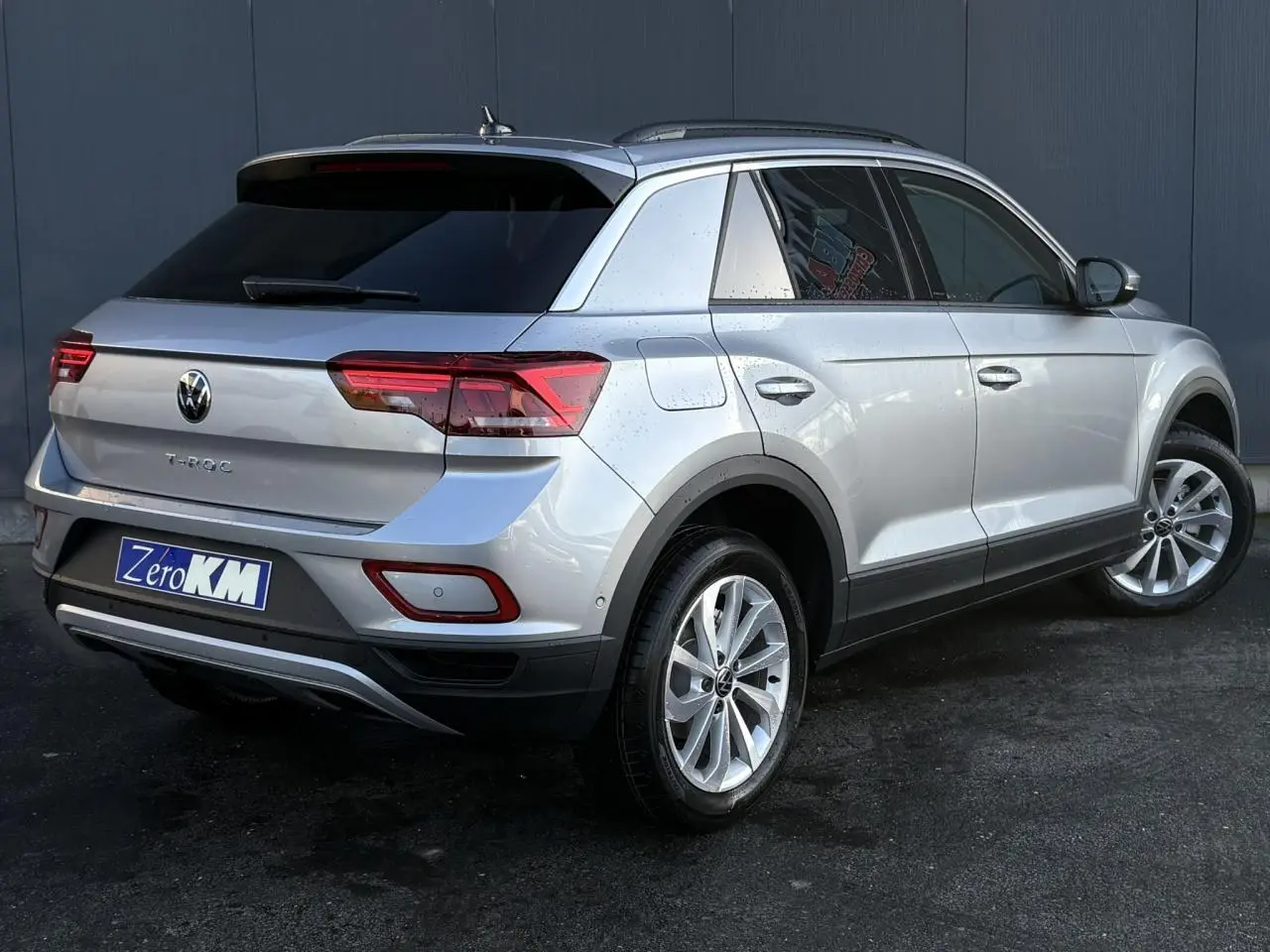 Volkswagen T-Roc argent Pyrite en 3/4 arrière droit, avec feux LED et jantes alliage visibles.