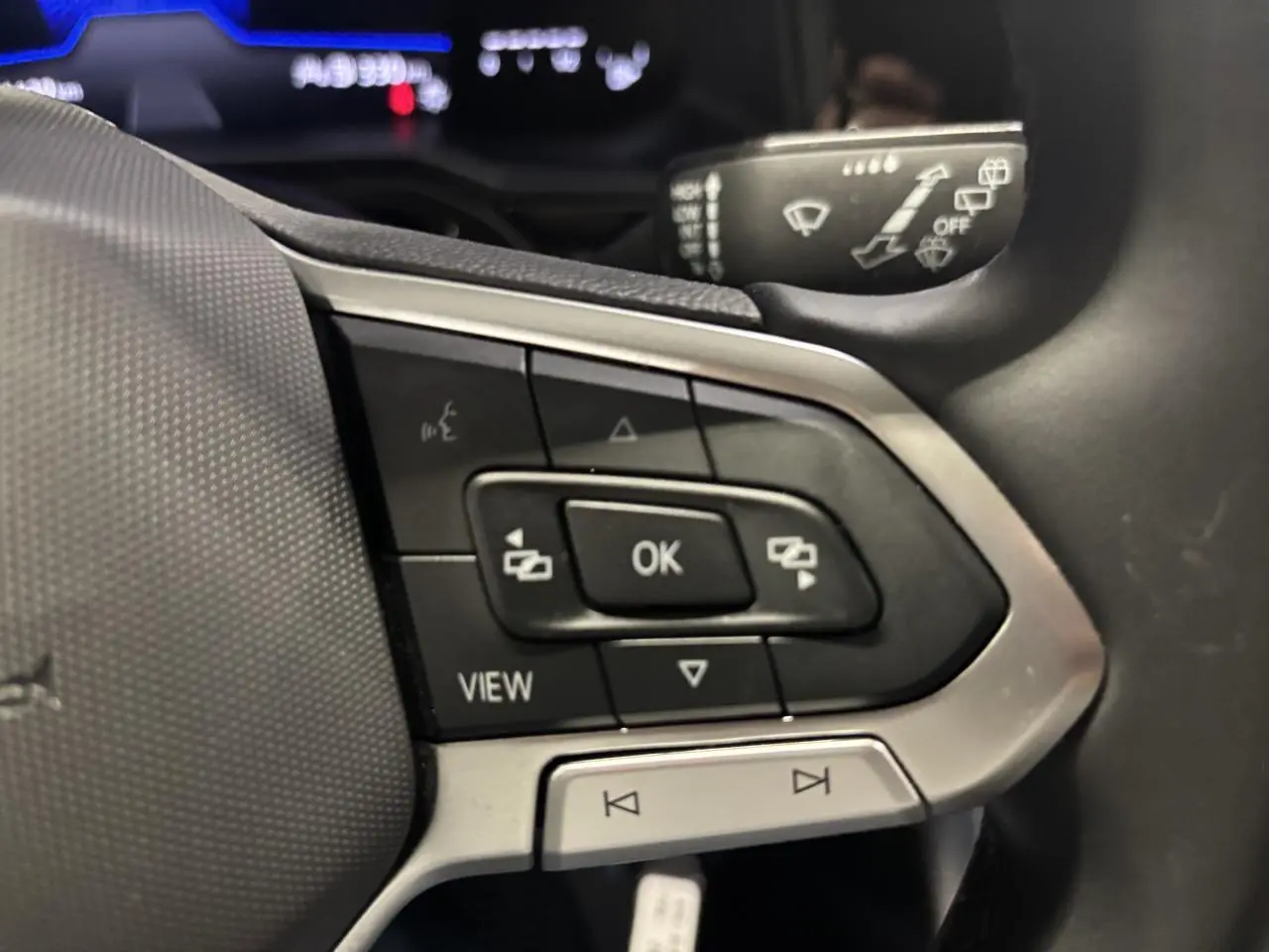 Gros plan sur les commandes du volant cuir multifonctions côté gauche du Volkswagen Taigo blanc 2023.