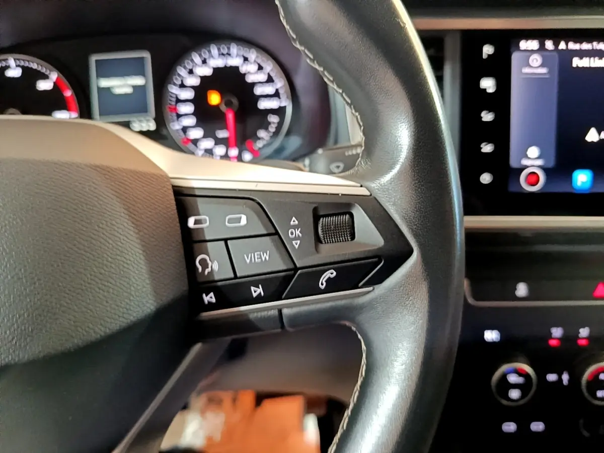 Gros plan sur le volant en cuir noir avec commandes multifonctions, tableau de bord et écran tactile du SEAT Ateca gris clair 2022.