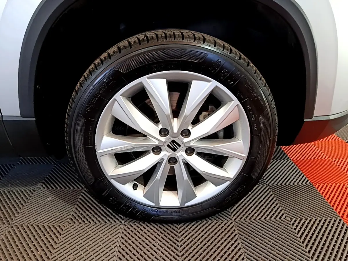 Gros plan sur la roue avant droite avec jante alliage argentée du SEAT Ateca gris clair 2022.