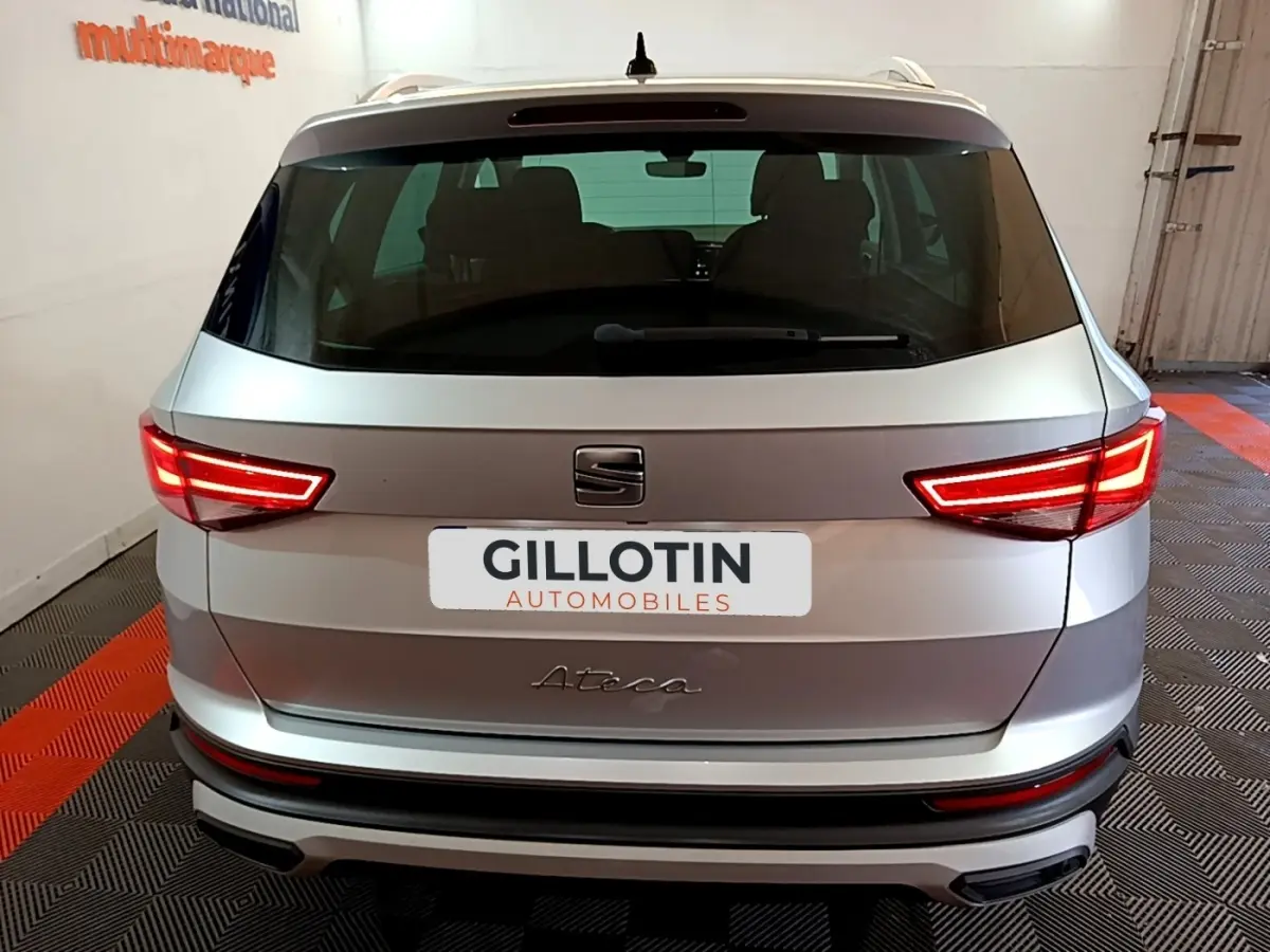 Vue arrière d'un SEAT Ateca gris clair 2022 avec feux LED allumés dans un garage.