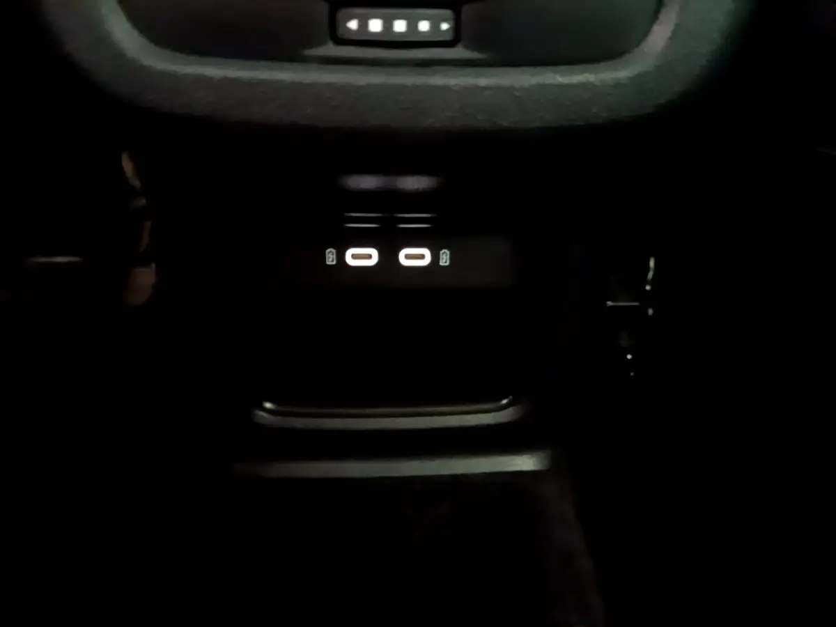 Gros plan sur la zone de recharge par induction avec ports USB-C éclairés dans l'habitacle sombre du SEAT Ateca gris.