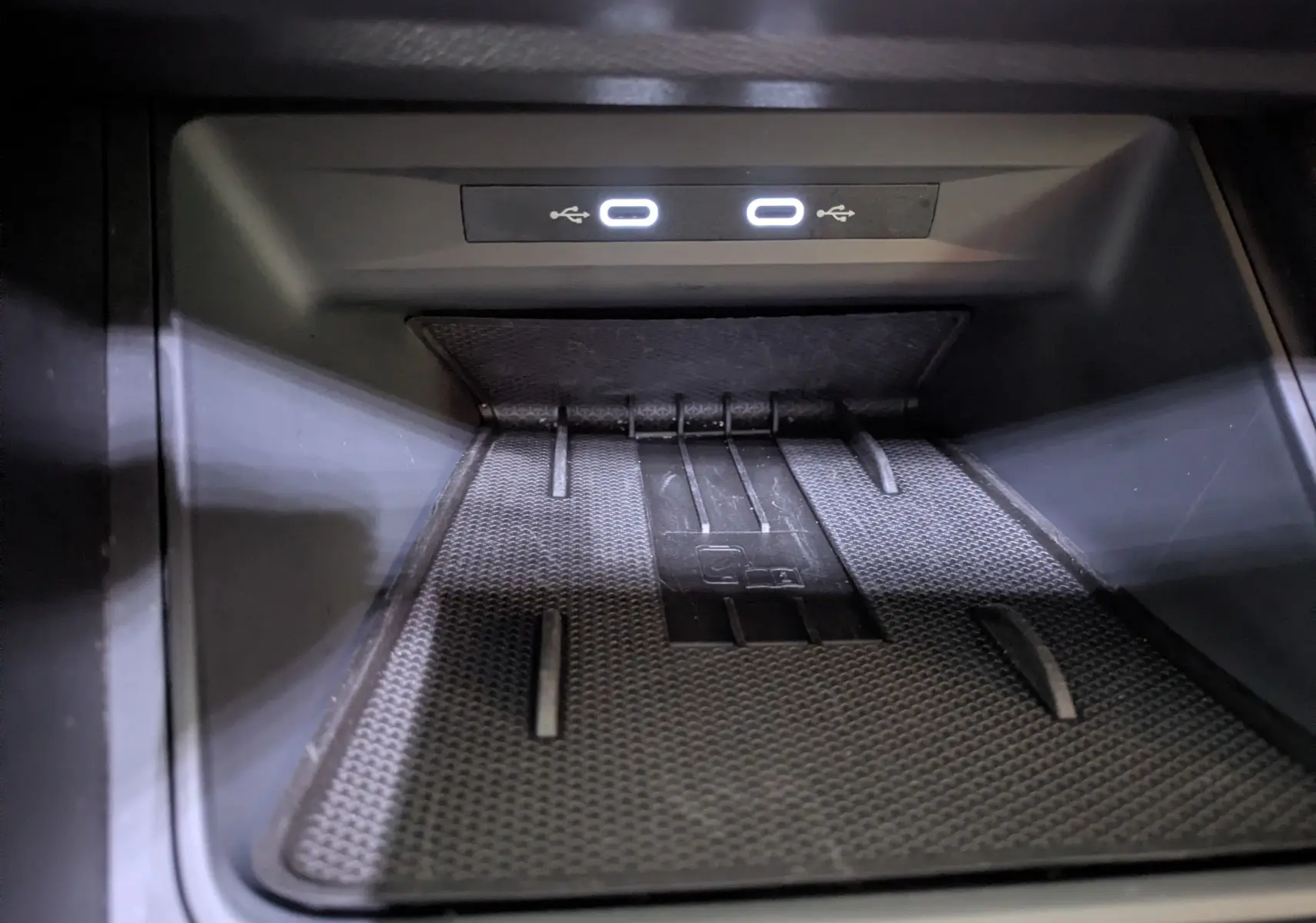 Gros plan sur la zone de recharge sans fil et ports USB lumineux dans l'habitacle noir du CUPRA Leon 2025.