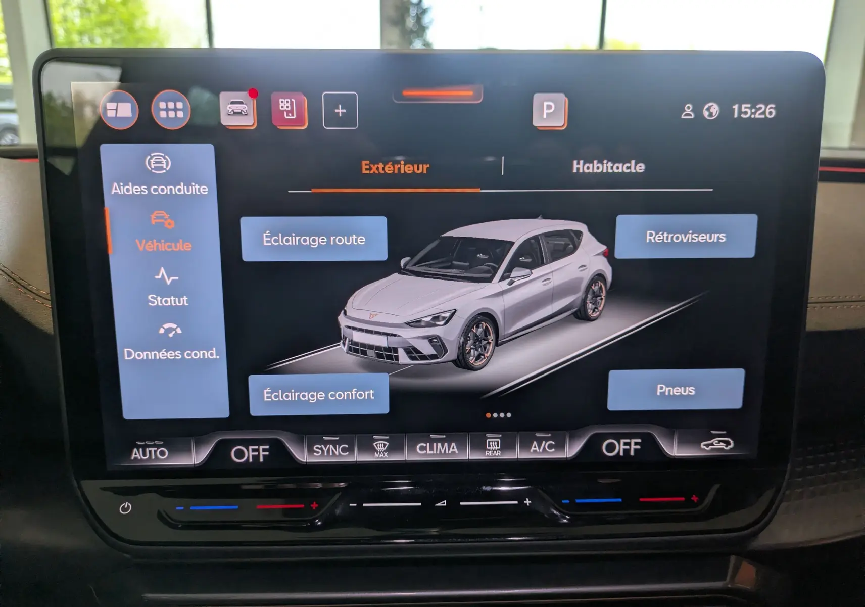 Écran tactile intérieur affichant une modélisation 3/4 avant d'une CUPRA Leon blanche avec options d'éclairage et pneus.