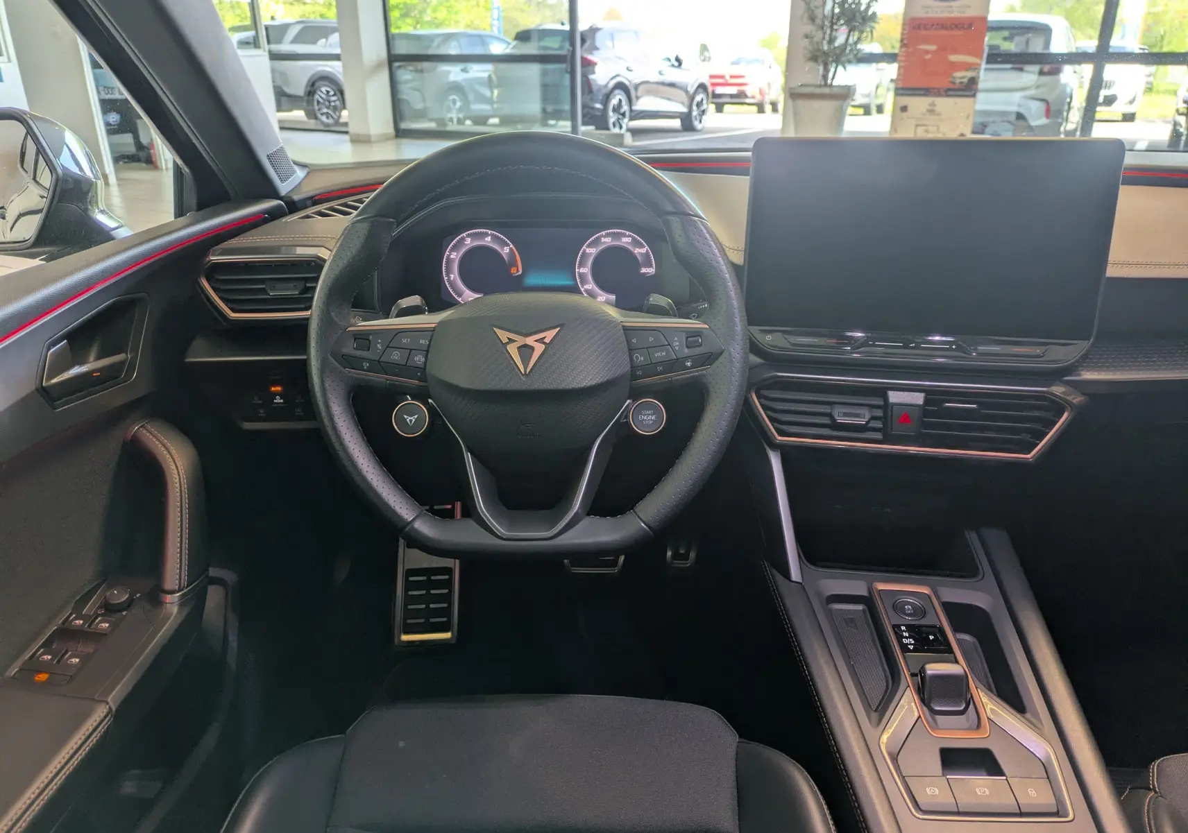 Vue intérieure centrée sur le volant et tableau de bord de la CUPRA Leon 2.0TDI noir avec écran tactile et sellerie mix cuir tissu.