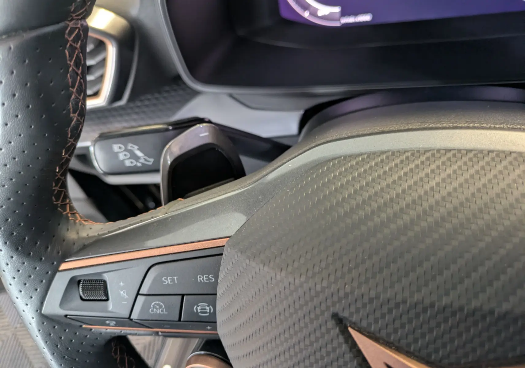 Gros plan sur le volant noir à surpiqûres cuivrées du Cupra Leon 2.0 TDI 150 DSG7 avec commandes intégrées.