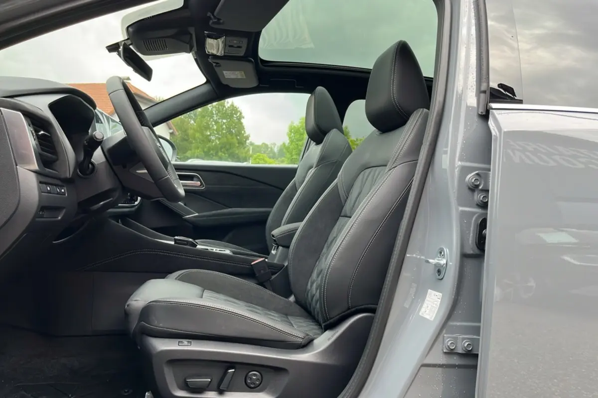 Vue intérieure côté conducteur du Nissan Qashqai E-POWER 205 Tekna Plus 2026, sièges cuir gris et toit panoramique ouvert.