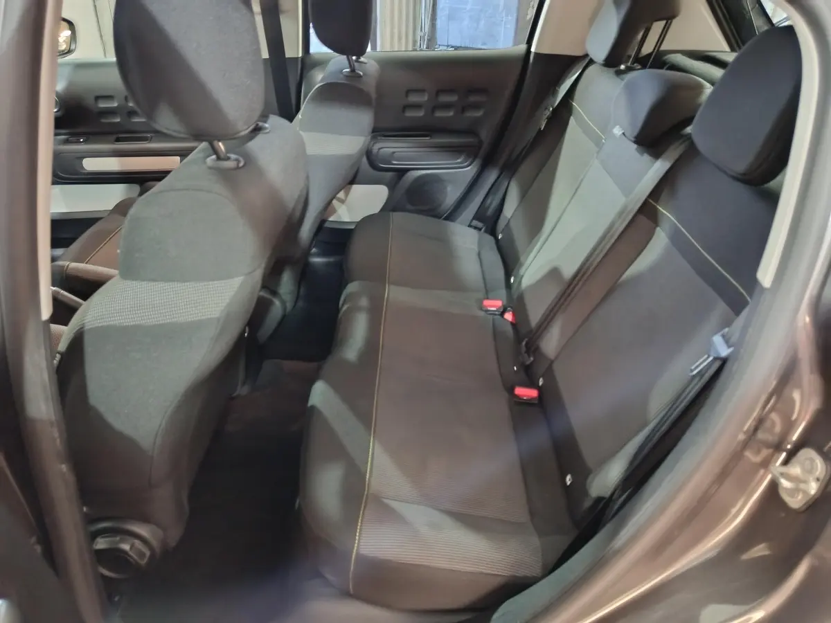 Vue intérieure côté droit sur la banquette arrière gris foncé de la Citroën C3 2024 avec sièges tissu et ceintures visibles.