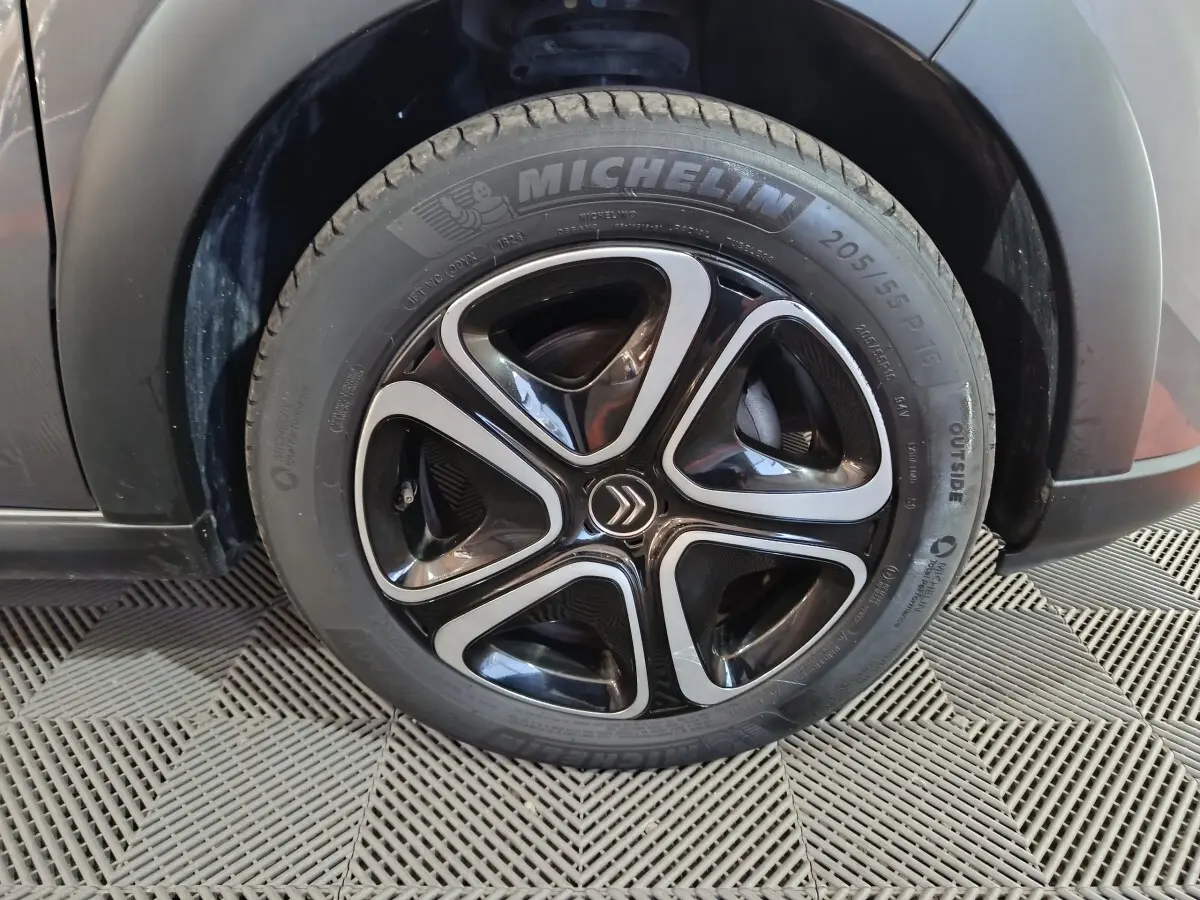 Gros plan sur la roue avant droite d'une Citroën C3 gris foncé avec jante noire et argentée au design moderne.