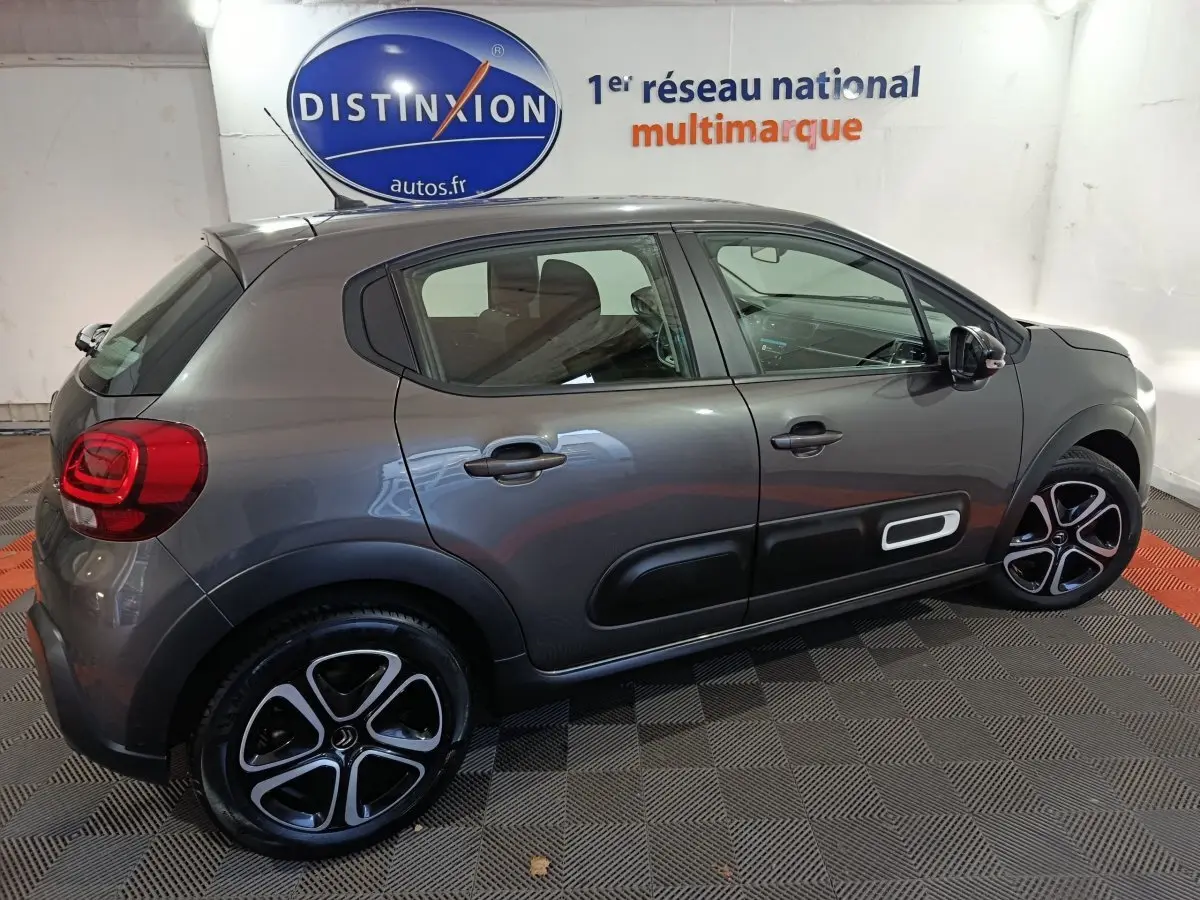 Vue latérale droite d'une Citroën C3 BlueHDi 100 BVM PLUS gris foncé avec jantes alliage et protections latérales noires.