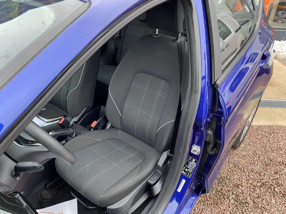 Vue intérieure côté conducteur d'une Ford Fiesta 2017 bleu foncé, avec siège tissu gris à motifs discrets.