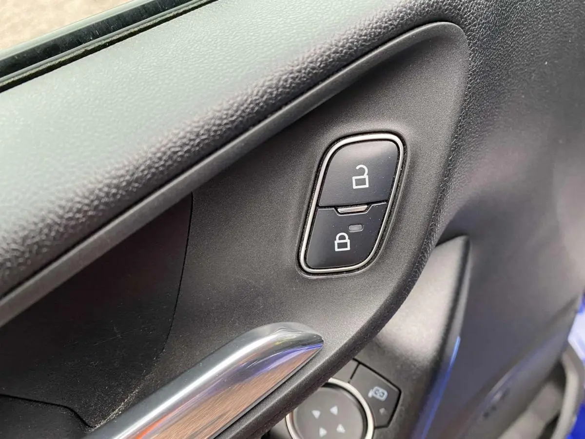 Détail intérieur de la porte côté conducteur de la Ford Fiesta 2017 bleu foncé, avec commandes de verrouillage et poignée chromée.