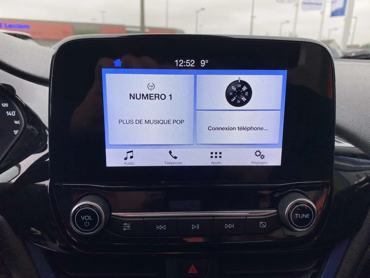 Écran tactile central de la Ford Fiesta 2017 bleu foncé affichant radio et connexion téléphone, vue de face intérieure.