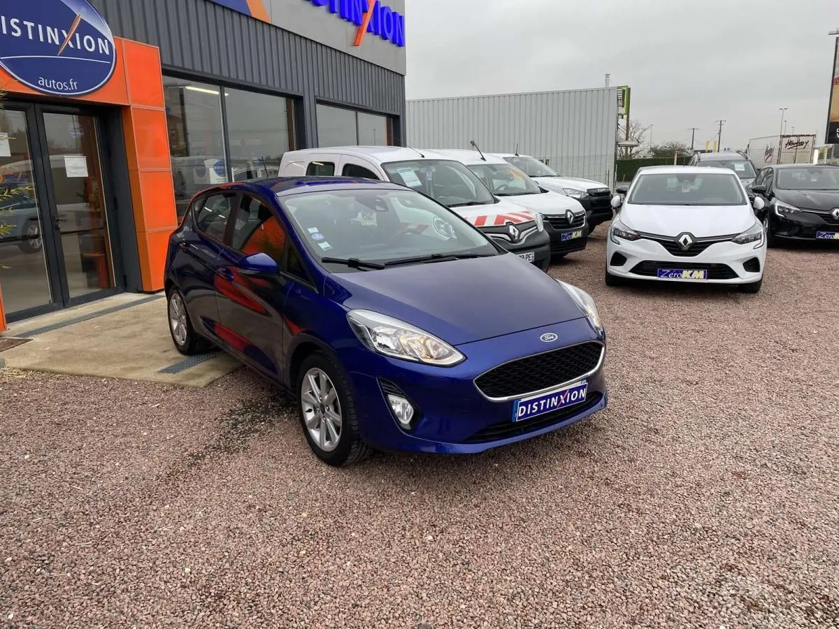 Ford Fiesta 2017 bleu foncé vue 3/4 avant droit, garée devant un concessionnaire avec plaque Distinxion.
