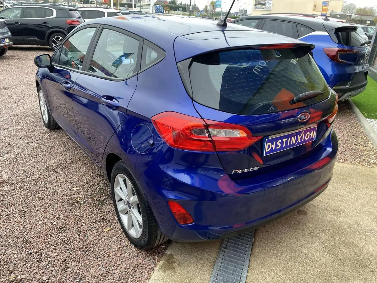 Vue 3/4 arrière gauche d'une Ford Fiesta bleu foncé 2017 avec feux arrière allongés et jantes argentées.