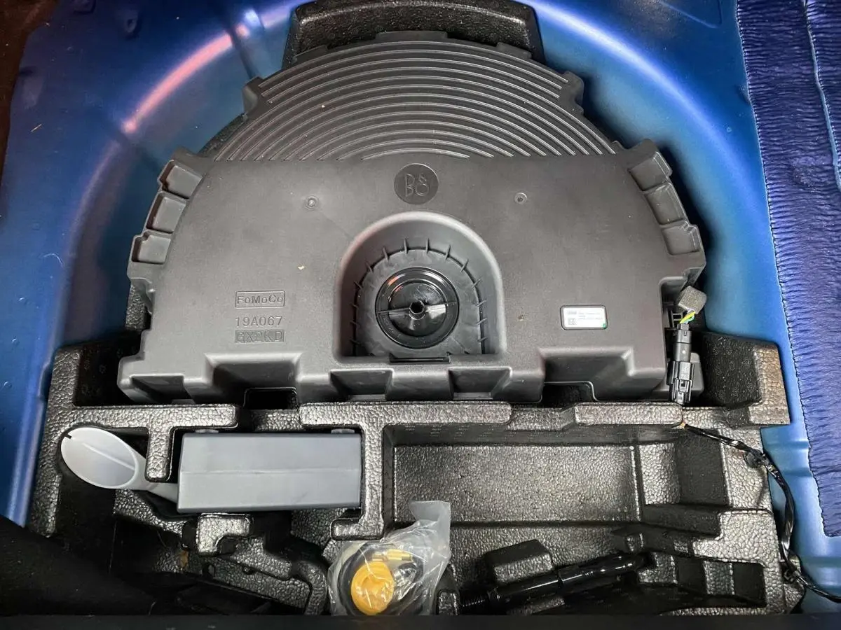 Vue plongeante sur le coffre d’une Ford Fiesta bleu foncé 2017, montrant le rangement sous la roue de secours.