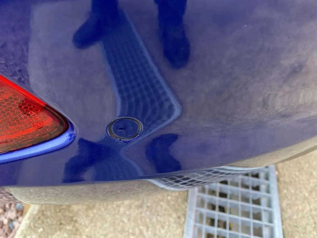 Gros plan sur l'angle arrière gauche d'une Ford Fiesta bleu foncé 2017, avec feu arrière et capteur de recul visibles.