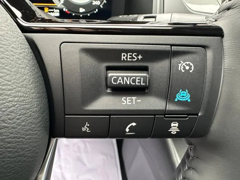 Gros plan sur les commandes au volant du Nissan Qashqai Hybrid e-POWER 2025, boutons noirs avec icônes blanches et bleues.