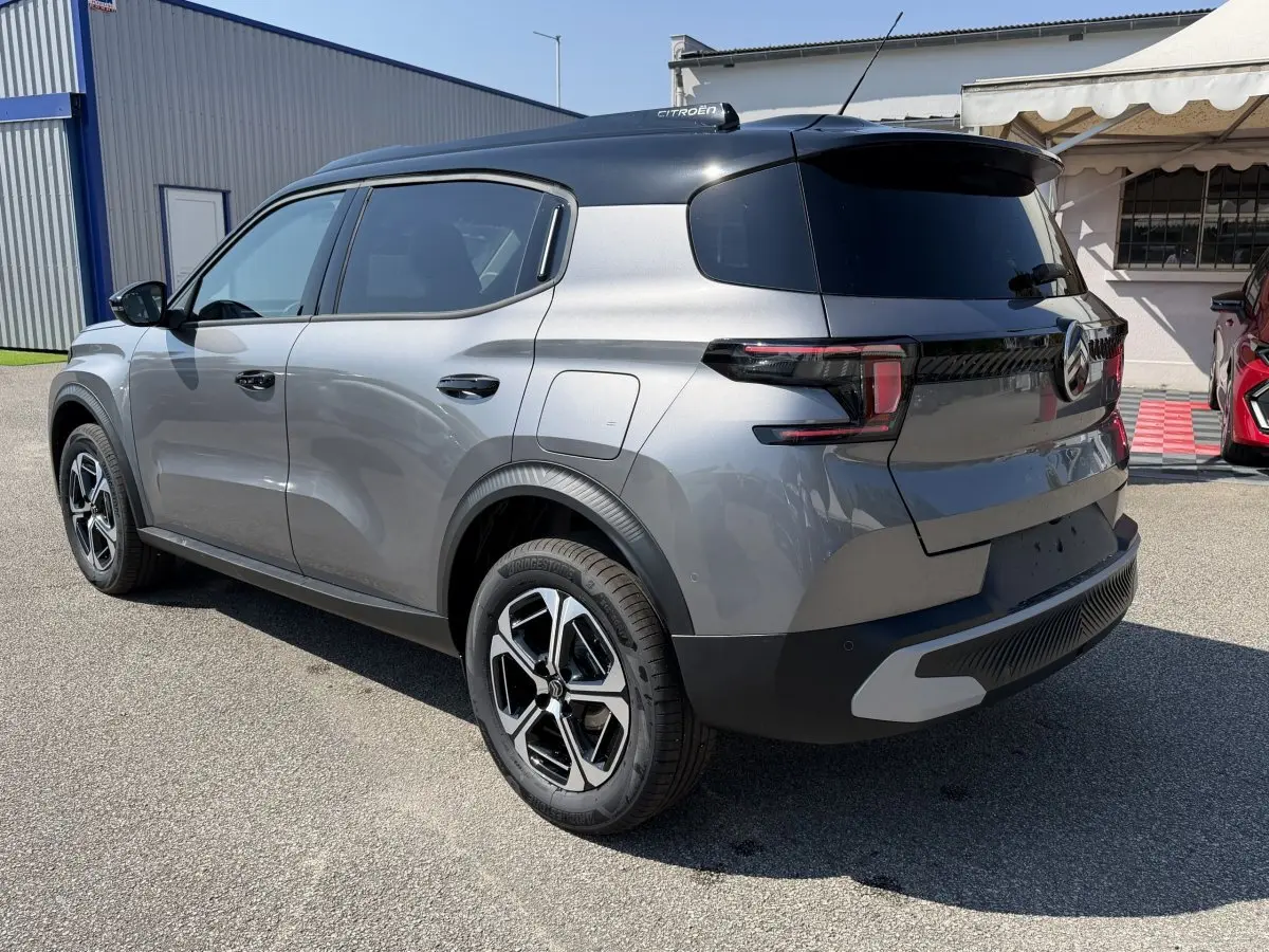 Citroën C3 Aircross gris clair vue 3/4 arrière droit, toit noir et jantes distinctives, stationnée en extérieur.