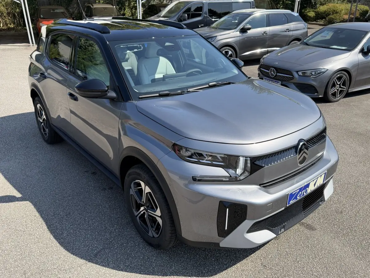 Citroën C3 Aircross gris clair vue 3/4 avant droit, avec toit noir et jantes distinctives, en extérieur sur parking.