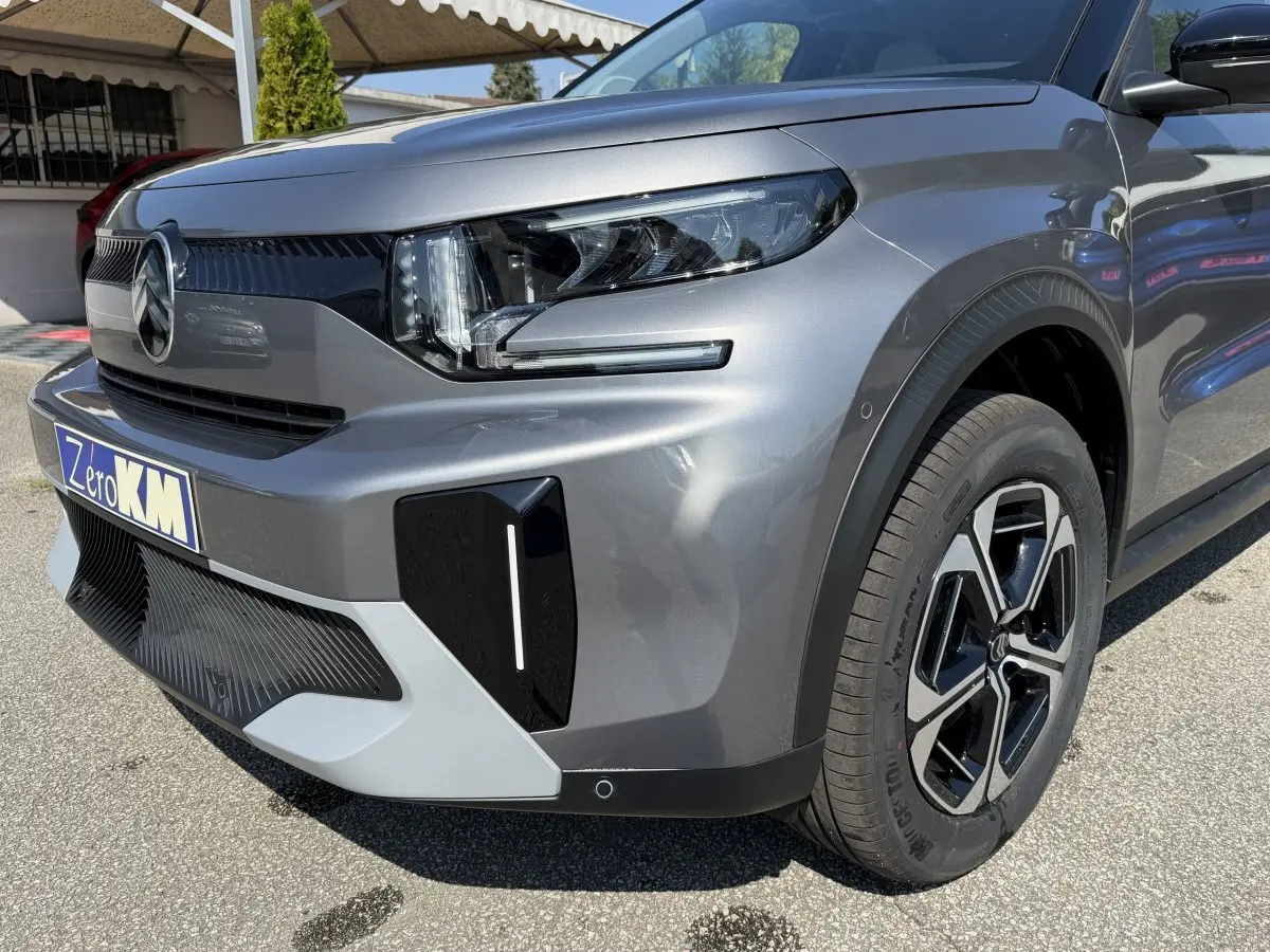 Vue 3/4 avant droit d'une Citroën C3 Aircross gris clair avec phares LED et jantes noires distinctives.