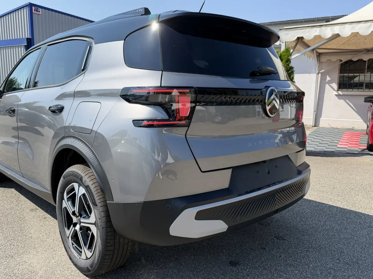 Vue 3/4 arrière droite d'un Citroën C3 Aircross gris clair avec feux LED et jantes distinctives.