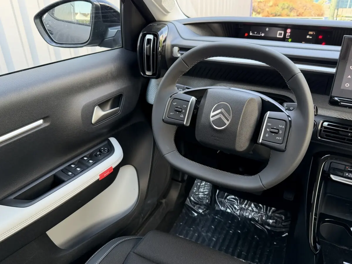 Vue intérieure côté conducteur du Citroën C3 Aircross gris clair, volant cuir multifonctions et tableau de bord numérique.