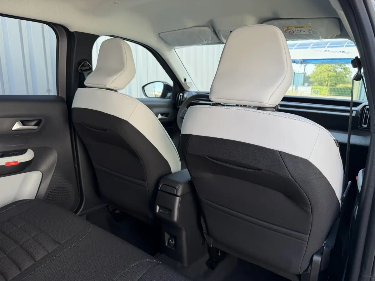 Vue arrière intérieure des sièges avant bicolores noir et blanc du Citroën C3 Aircross gris clair 2026 hybride.