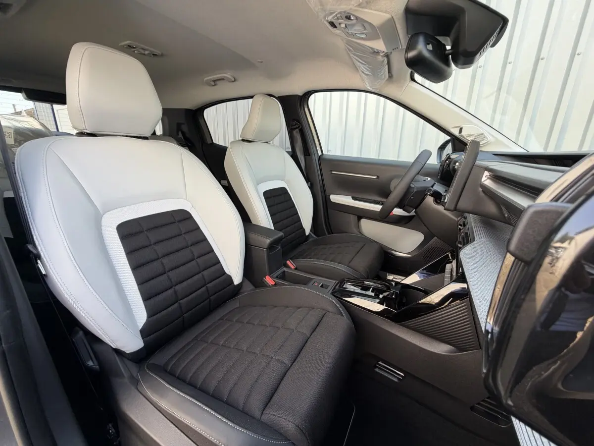 Vue intérieure côté conducteur de la Citroën C3 Aircross 2026, sièges bicolores noir et blanc avec tableau de bord moderne.