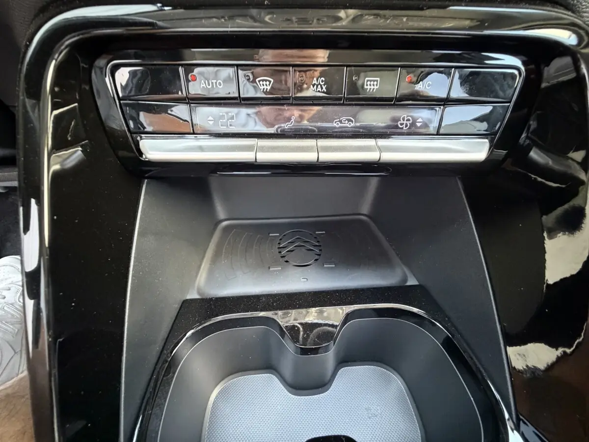 Vue rapprochée de la console centrale noire du Citroën C3 Aircross hybride, avec zone de recharge par induction visible.