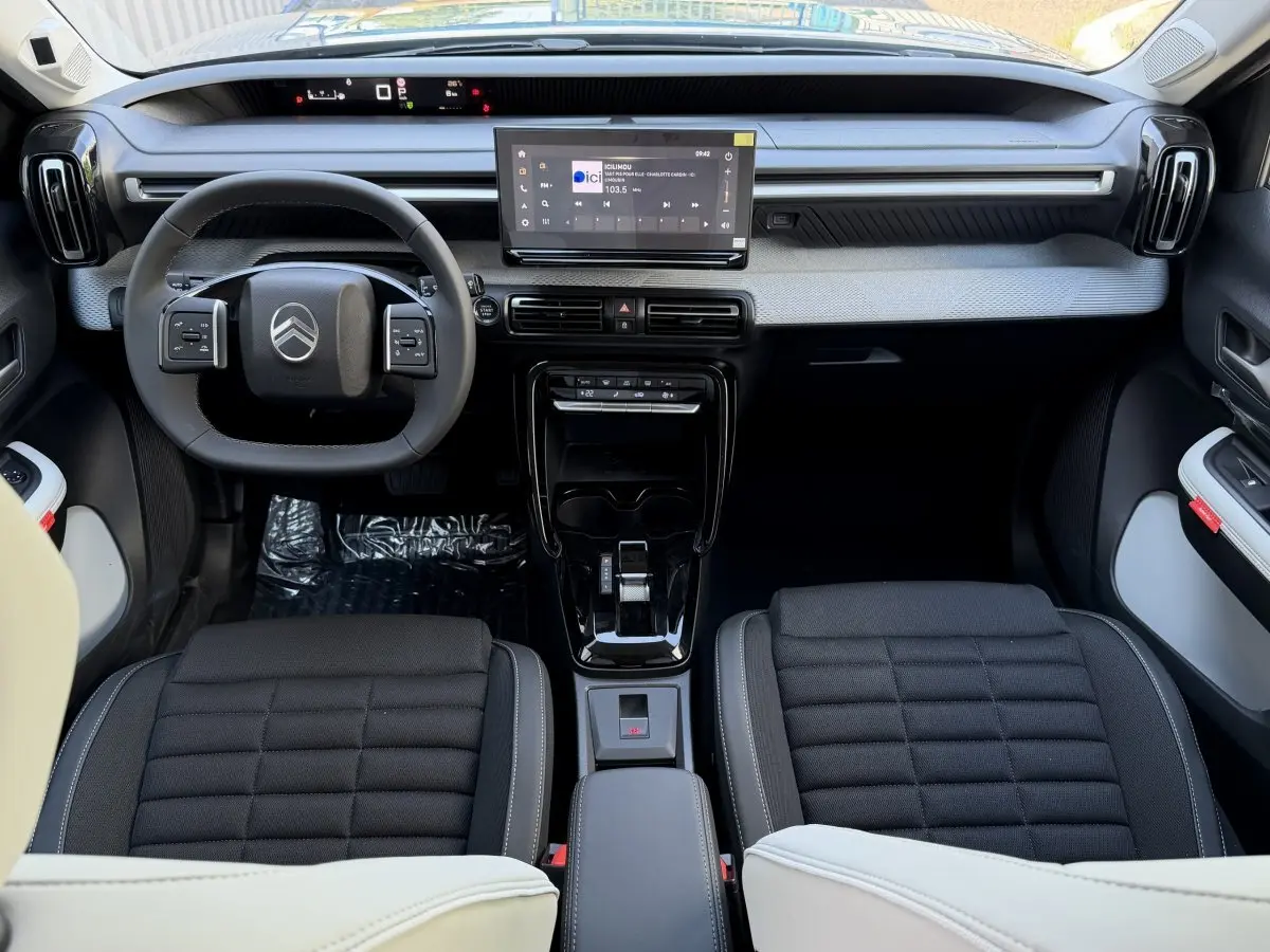 Vue intérieure avant de la Citroën C3 Aircross hybride 2026, tableau de bord moderne avec écran tactile central et volant cuir noir.