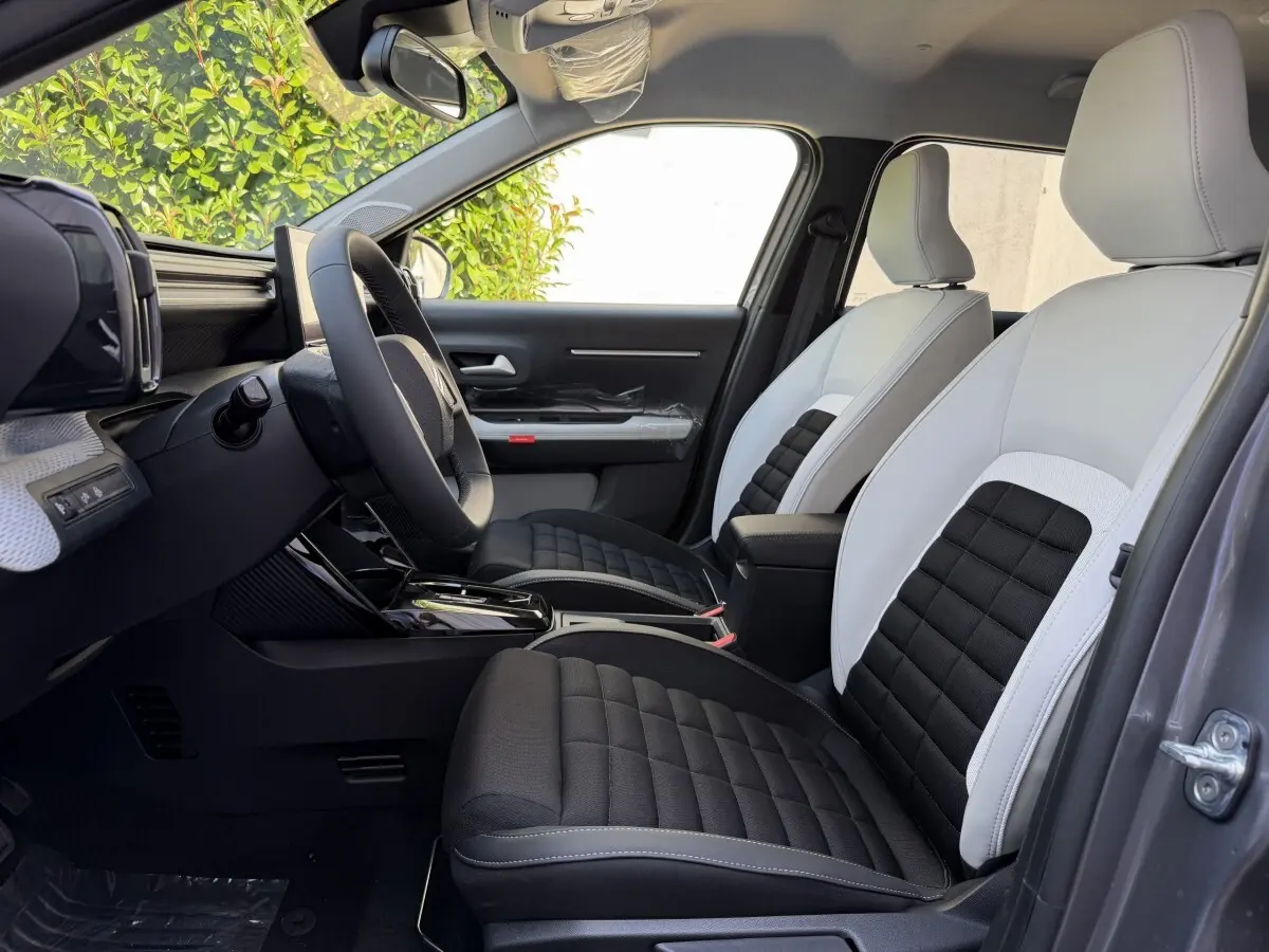 Vue intérieure côté conducteur de la Citroën C3 Aircross gris clair, sièges bicolores noir et blanc avec volant cuir multifonctions.