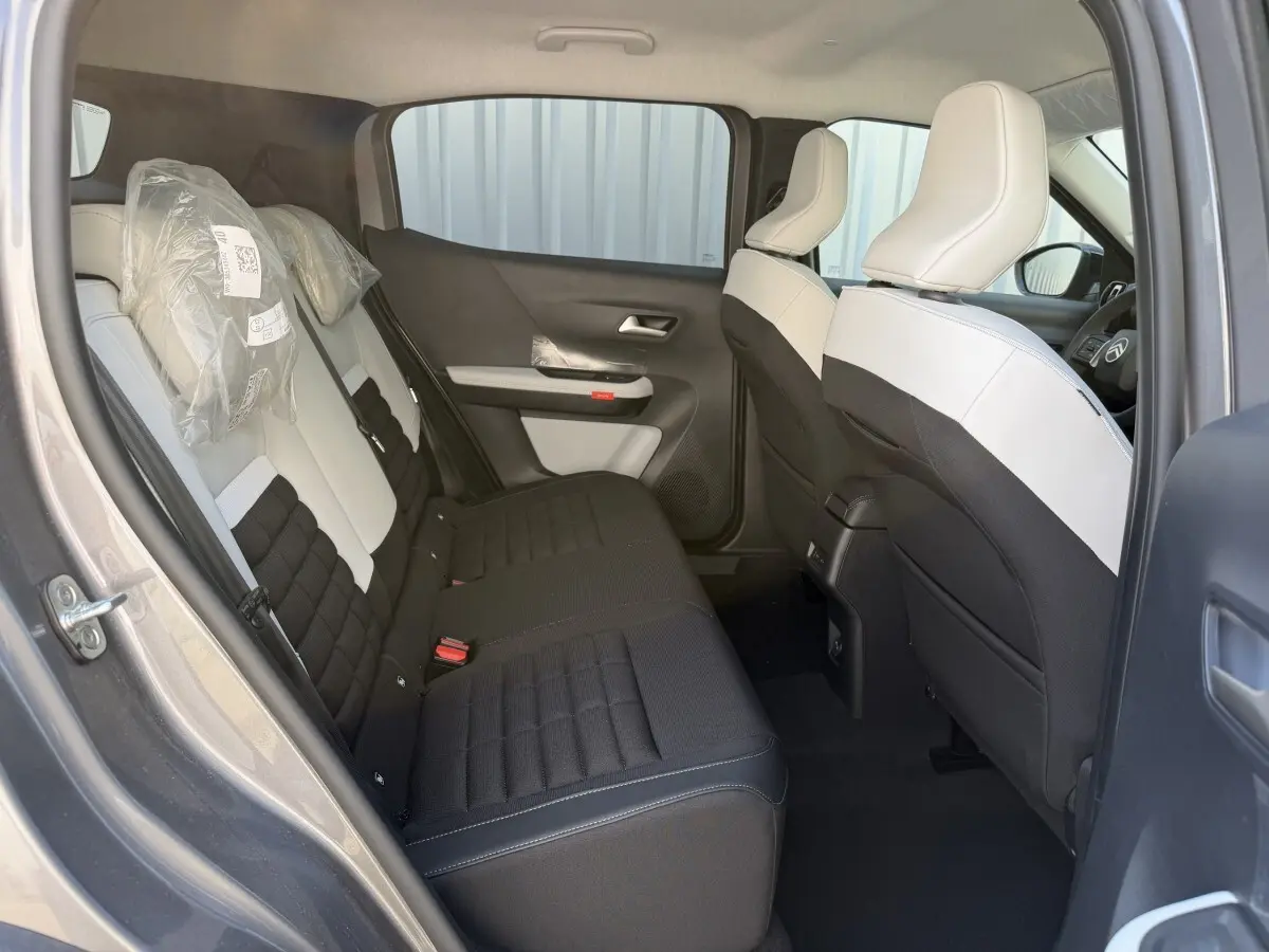 Vue intérieure arrière côté gauche du Citroën C3 Aircross gris clair, sièges bicolores noir et blanc avec appuie-têtes protégés.