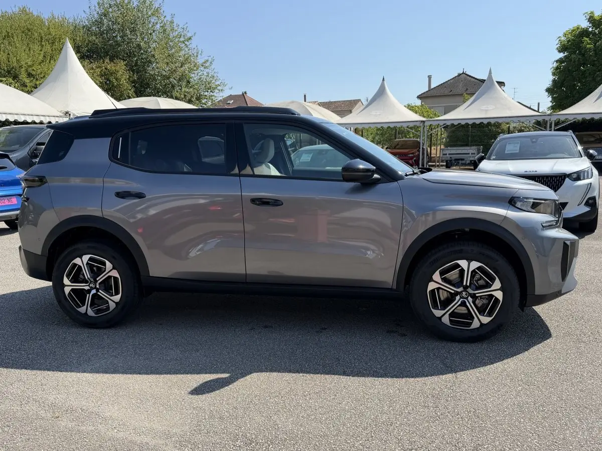 Profil côté gauche d'un Citroën C3 Aircross gris clair 2026 avec toit noir et jantes distinctives bicolores.