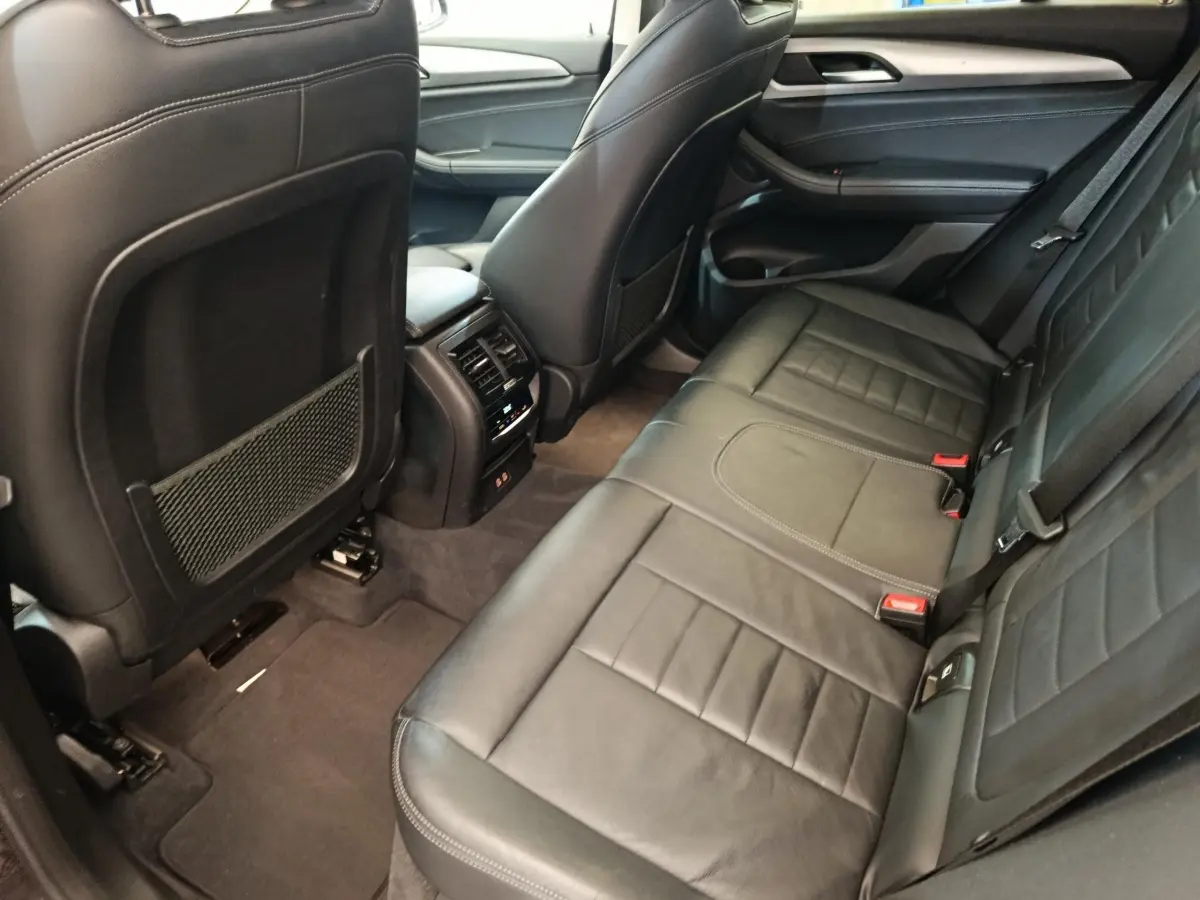 Vue intérieure côté droit des sièges arrière en cuir noir du BMW X3 xDrive20d 2020 avec console centrale et aérateurs.