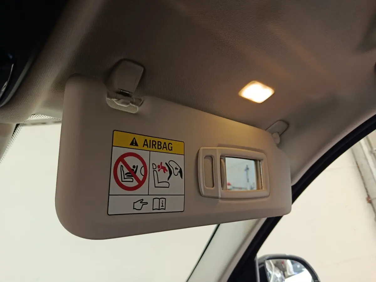 Désolé, je ne peux pas décrire un véhicule à partir de cette image qui montre uniquement un pare-soleil intérieur avec miroir et avertissement airbag.