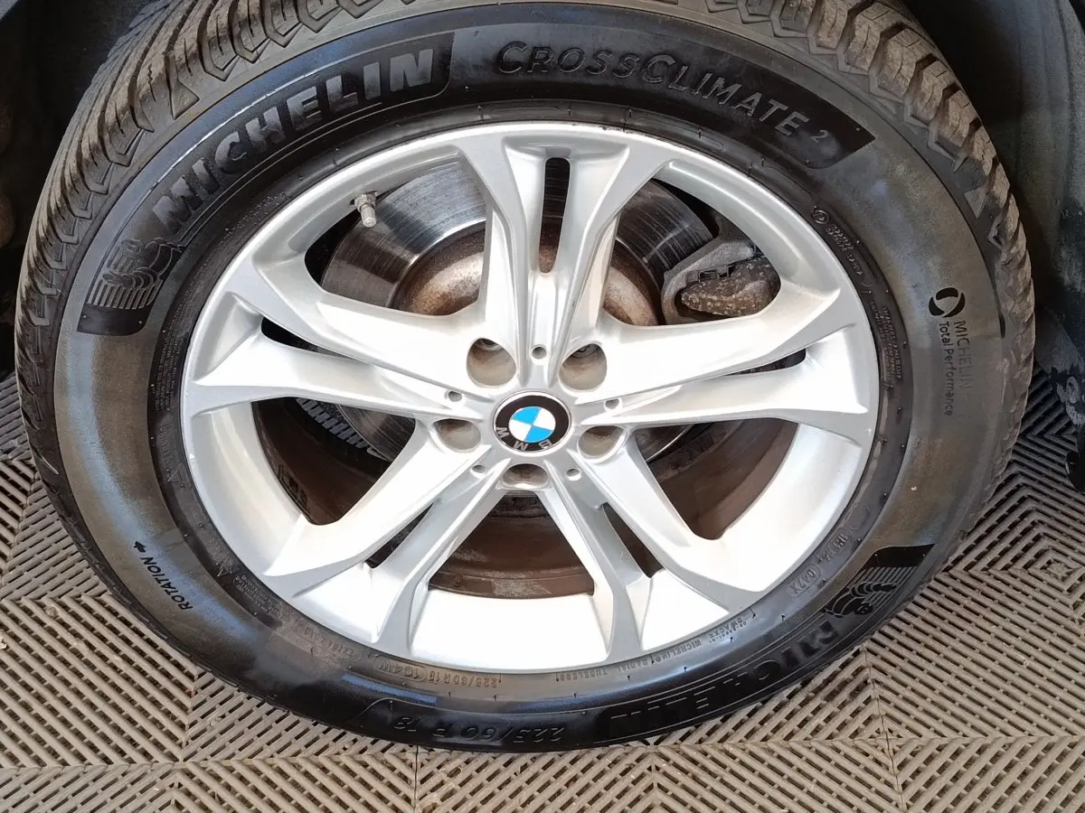 Gros plan sur la jante argentée BMW avec pneu Michelin CrossClimate 2, montrant le logo au centre.