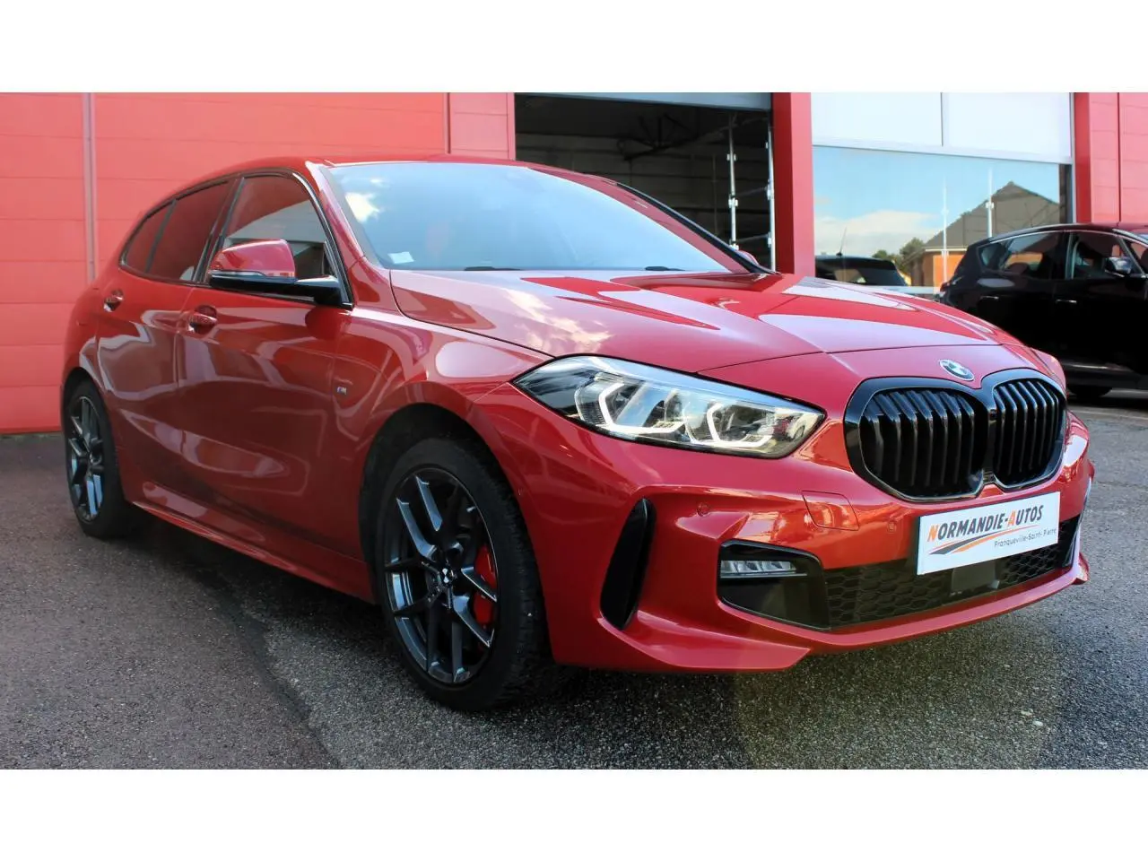 BMW Série 1 118d rouge Melbourne vue 3/4 avant avec jantes 18 pouces et freins M Sport rouges