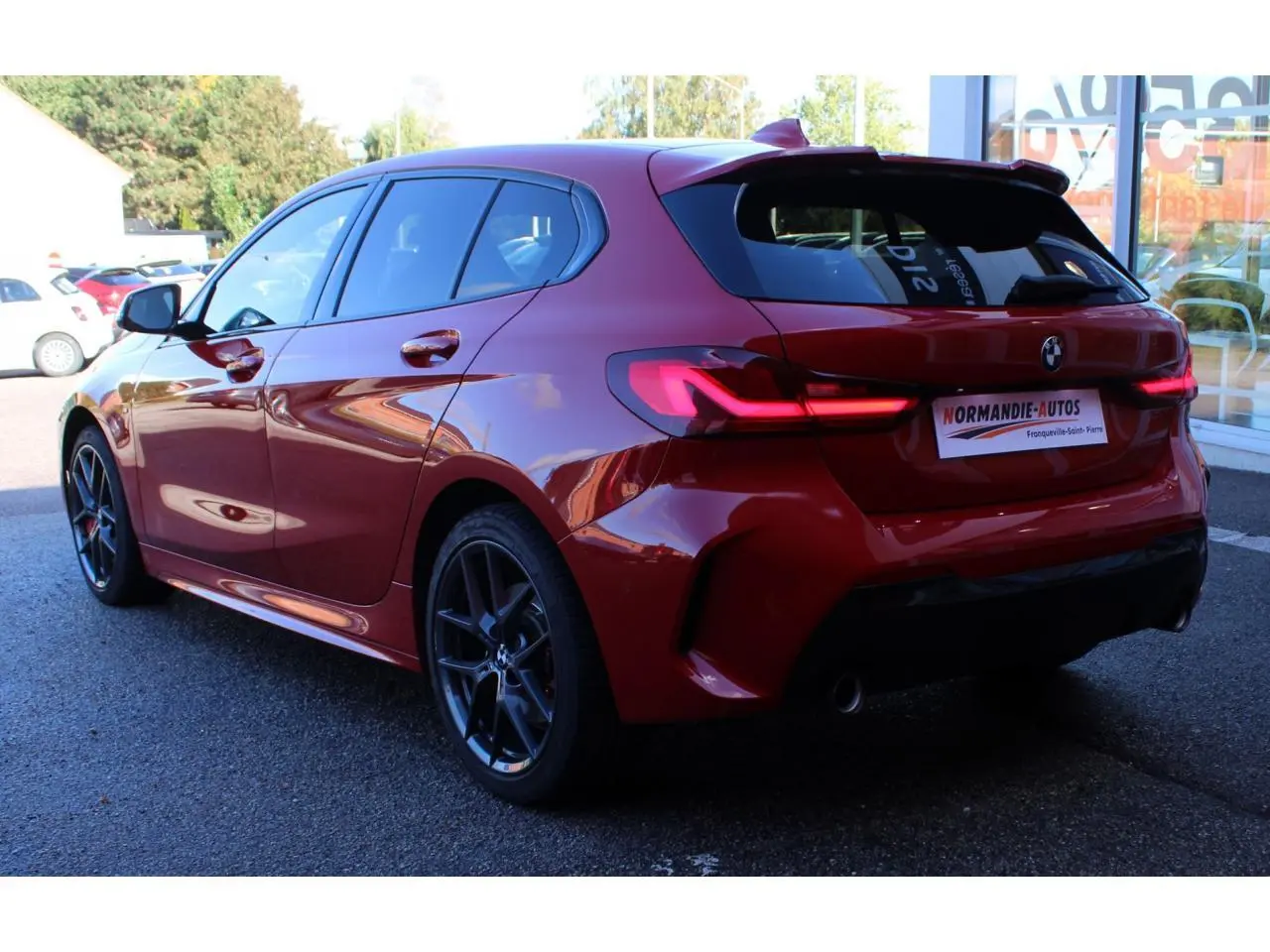 BMW Série 1 118d Edition M Sport Pro vue 3/4 arrière côté gauche en Melbourne Rot métallisé avec jantes gris ferric.