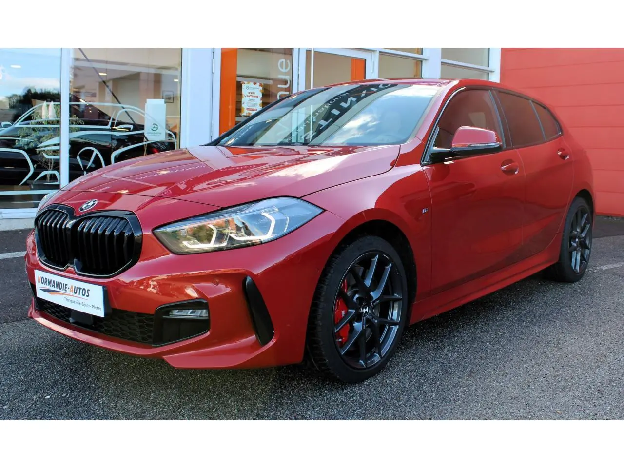 BMW Série 1 118d rouge Melbourne métallisé vue 3/4 avant droit avec jantes alliage et freins rouges M Sport