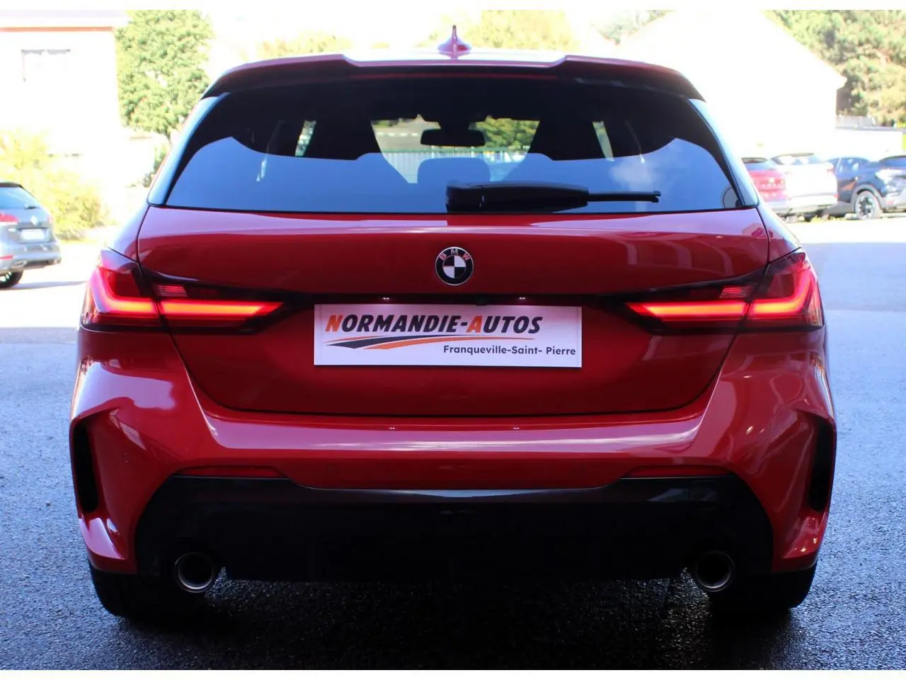 Vue arrière d'une BMW Série 1 118d rouge Melbourne avec feux LED allumés et double sortie d'échappement.