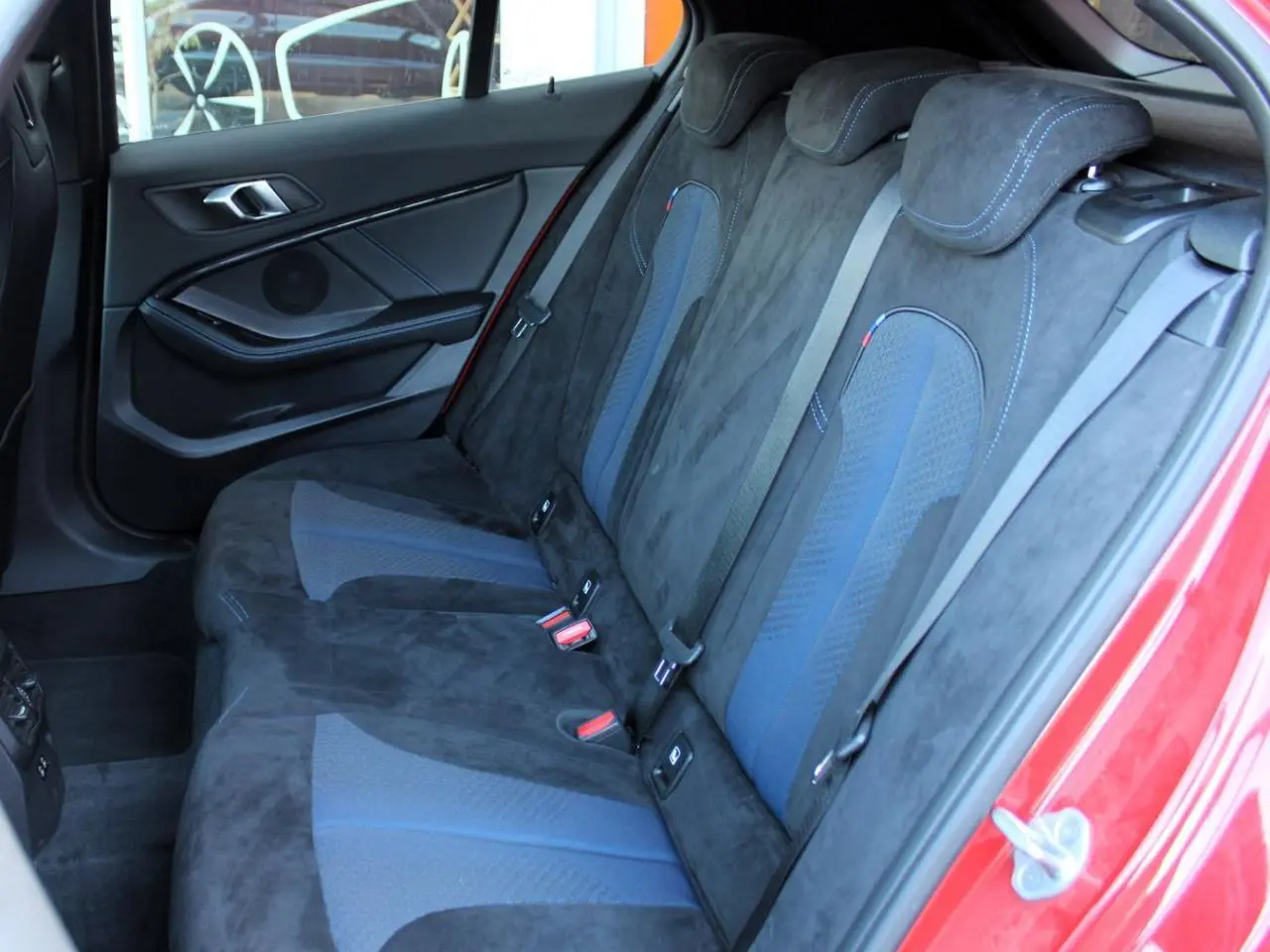 Vue intérieure côté gauche des sièges arrière en tissu Alcantara noir et bleu d'une BMW Série 1 118d Melbourne Rot.