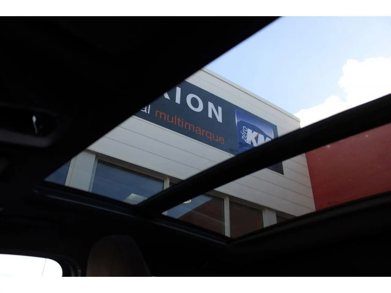 Vue intérieure du toit ouvrant panoramique ouvert de la BMW Série 1 118d Melbourne Rot, mettant en valeur la luminosité naturelle.